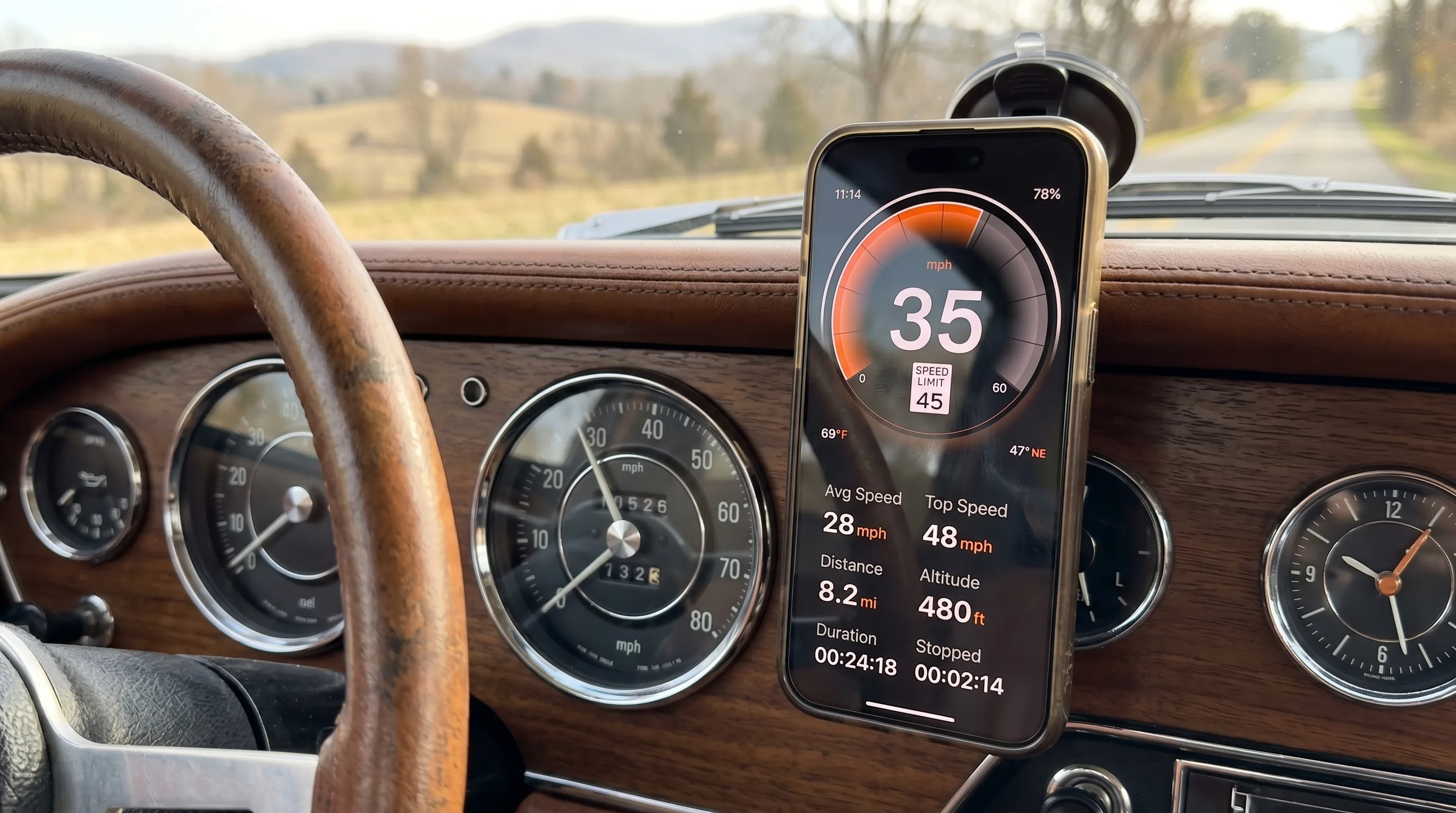 Salpicadero de coche clásico con embellecedores cromados y velocímetro analógico, con un iPhone moderno montado al lado mostrando GPS Speedometer con la velocidad real